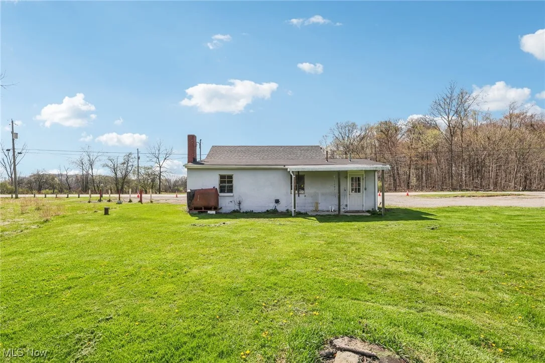 Back of house with a lawn, a chimney, and stucco siding
