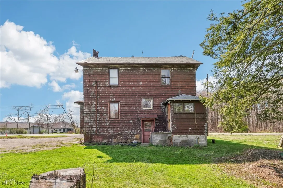 Rear view of property with a chimney and a yard