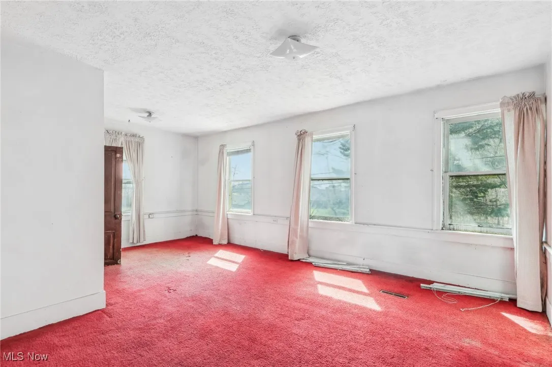 Carpeted empty room with plenty of natural light, a textured ceiling, and visible vents