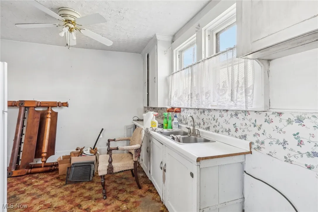 Kitchen featuring a sink, a textured ceiling, white cabinetry, ceiling fan, and light countertops