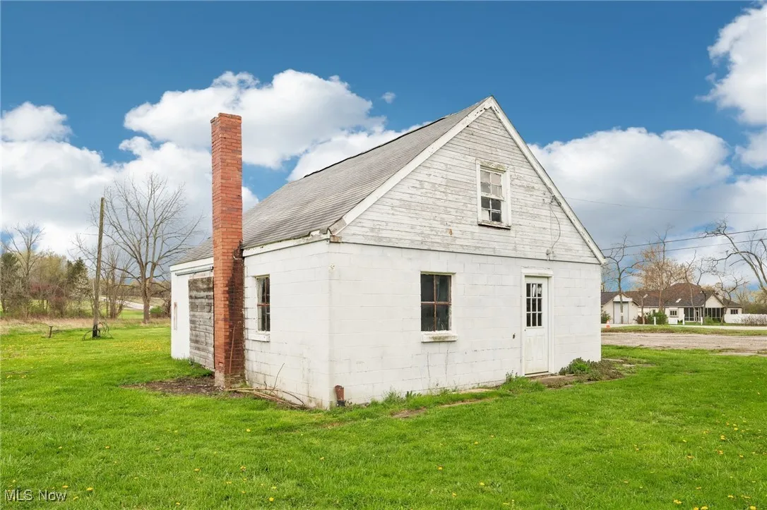 View of home's exterior featuring a lawn and a chimney