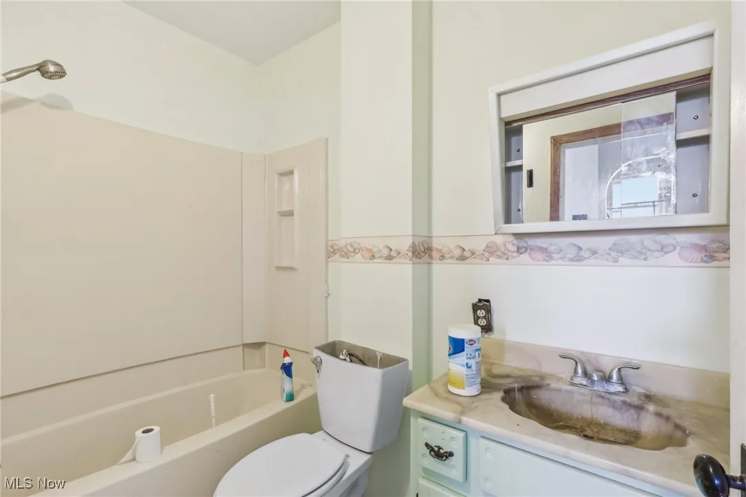 Bathroom with toilet, vanity, and  shower combination