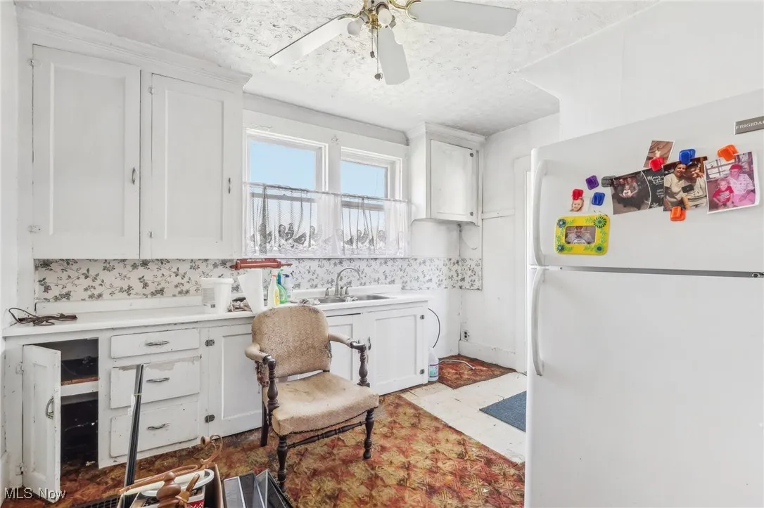 Kitchen with white cabinetry, a sink, light countertops, and freestanding refrigerator