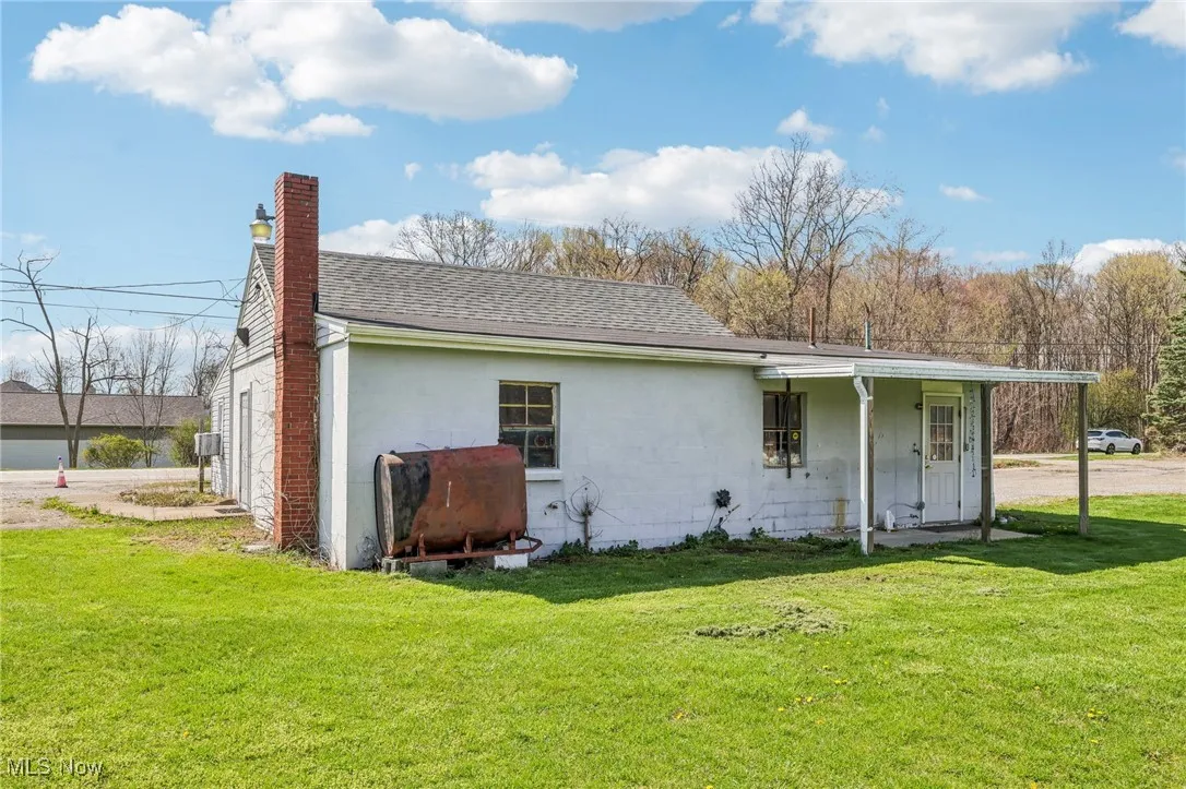 Rear view of property featuring a lawn, a chimney, and a shingled roof