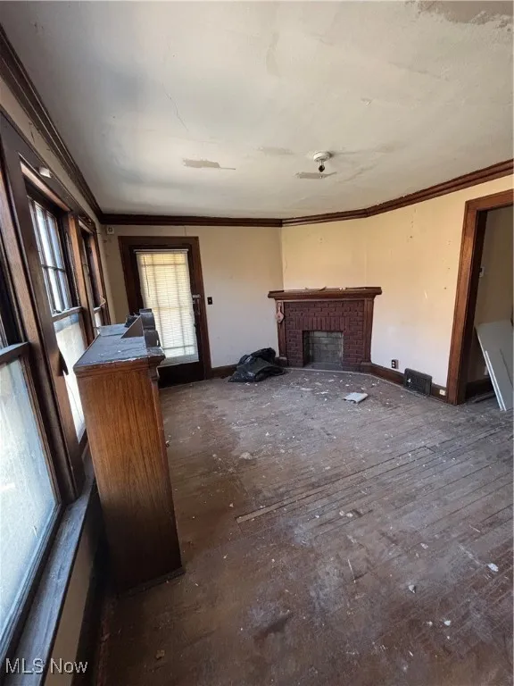 Unfurnished living room featuring baseboards, crown molding, and a fireplace