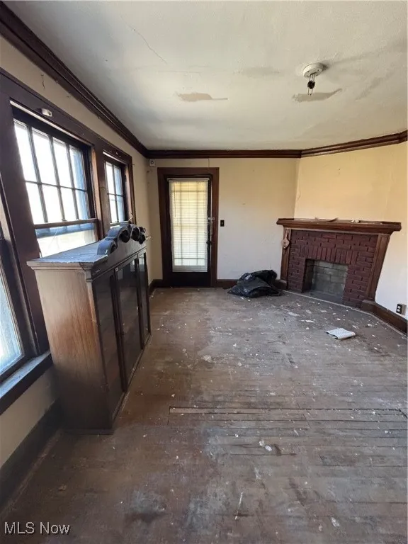 Unfurnished living room with baseboards, ornamental molding, and a fireplace