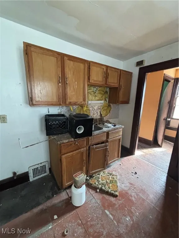 Kitchen featuring brown cabinets, baseboards, and visible vents