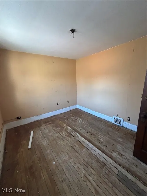 Unfurnished room with baseboards, hardwood / wood-style flooring, and visible vents