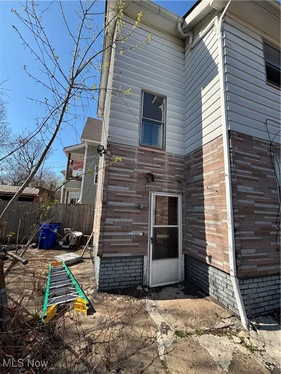 Rear view of property featuring brick siding and fence