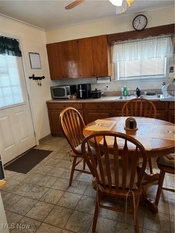 Kitchen featuring brown cabinets, plenty of natural light, crown molding, and ceiling fan