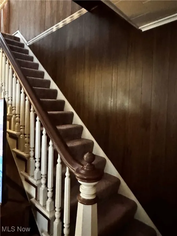 Staircase featuring wood walls