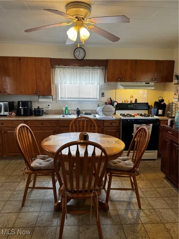 Kitchen featuring tasteful backsplash, ventilation hood, range, and ceiling fan