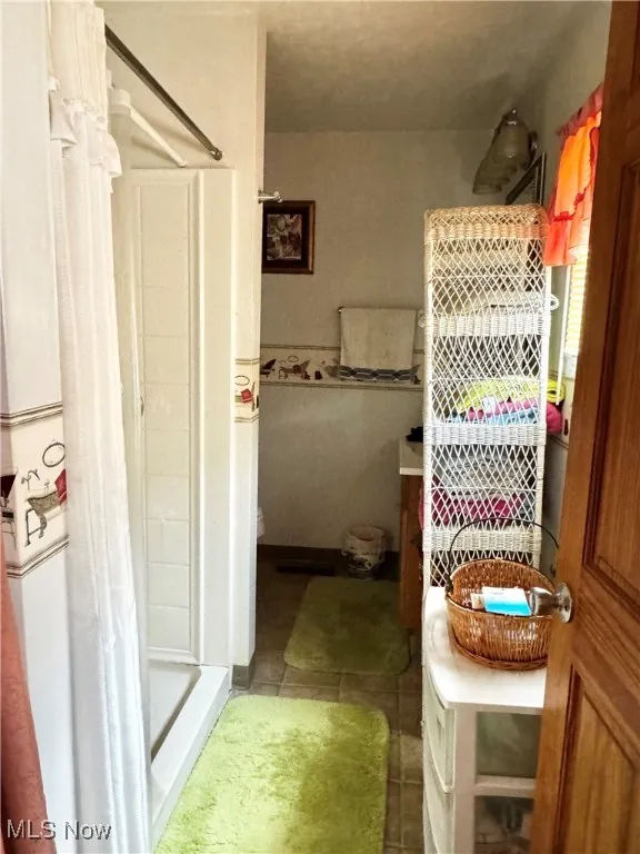 Full bath featuring a shower stall and tile patterned floors