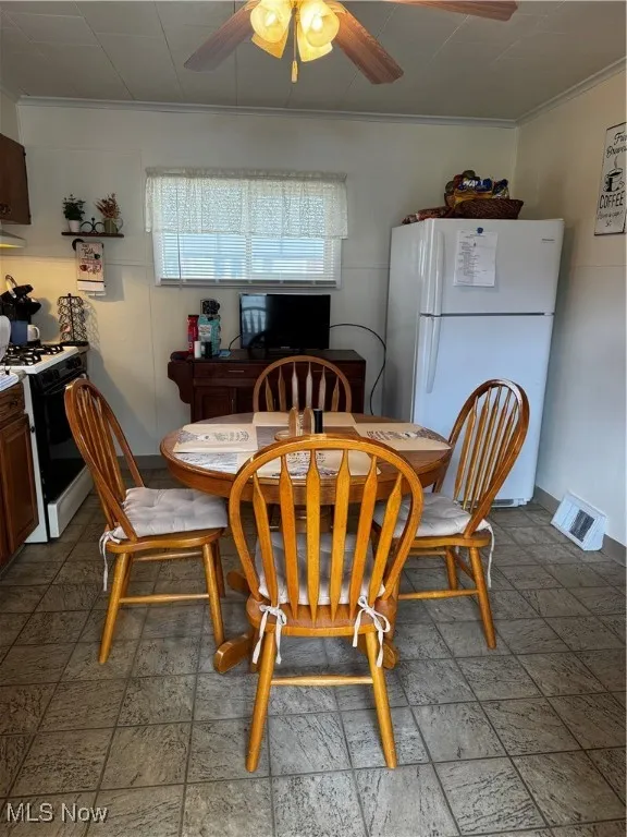 Dining room with ceiling fan, visible vents, and ornamental molding