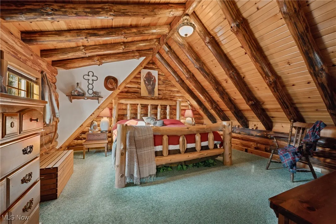 Unfurnished bedroom with lofted ceiling with beams, wooden ceiling, and carpet floors