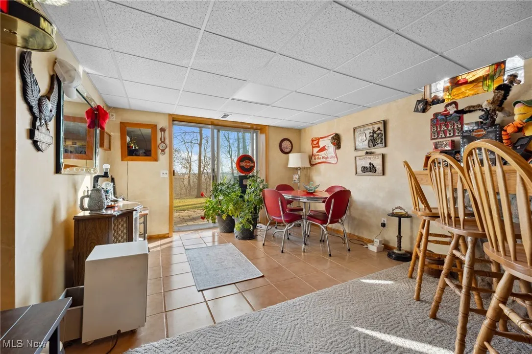Dining room featuring tile patterned flooring, a drop ceiling, and baseboards