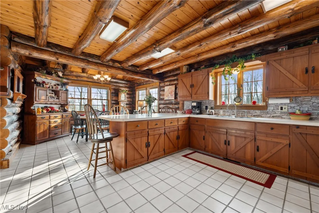 Kitchen featuring a peninsula, light countertops, wooden ceiling, and log walls