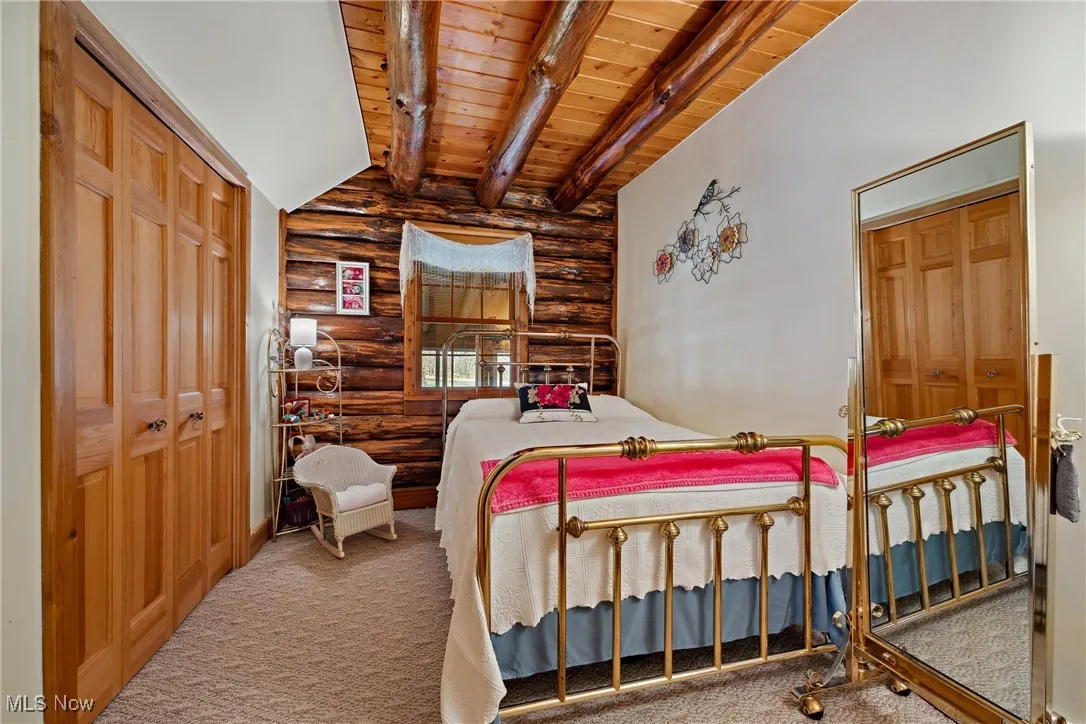 Bedroom featuring beam ceiling, wooden ceiling, a closet, and carpet