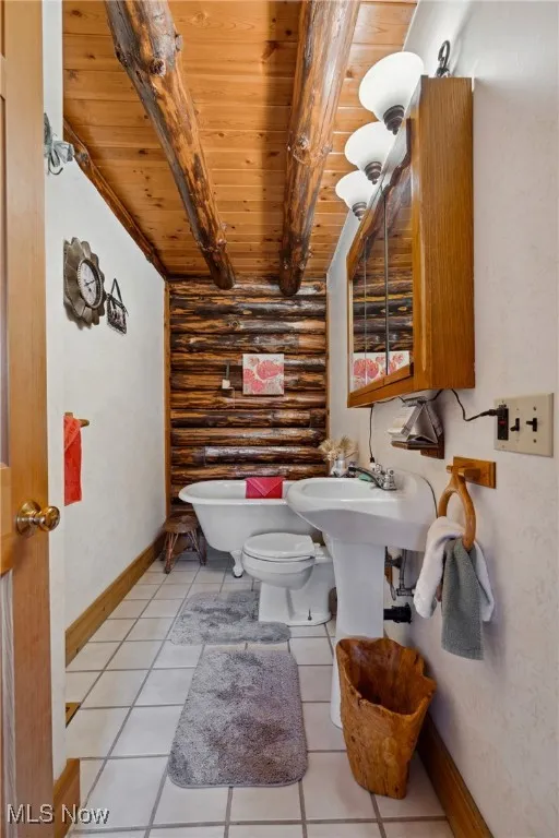 Bathroom featuring baseboards, log walls, wood ceiling, beamed ceiling, and toilet