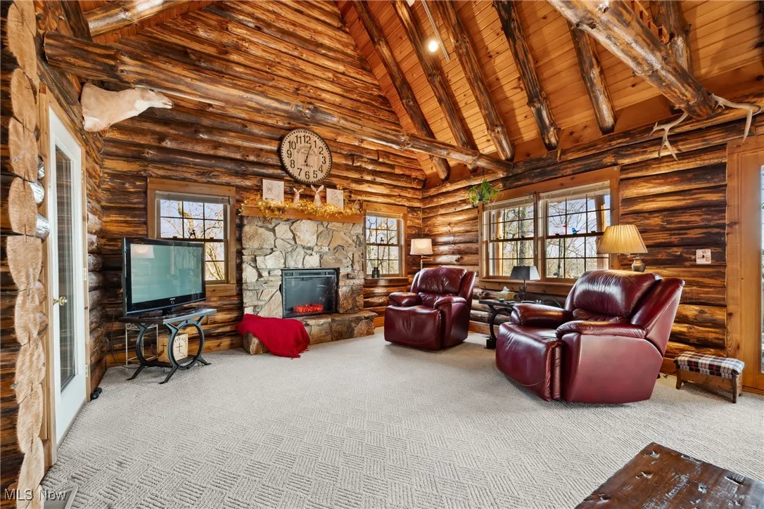 Carpeted living area featuring plenty of natural light, beamed ceiling, a fireplace, and wooden ceiling