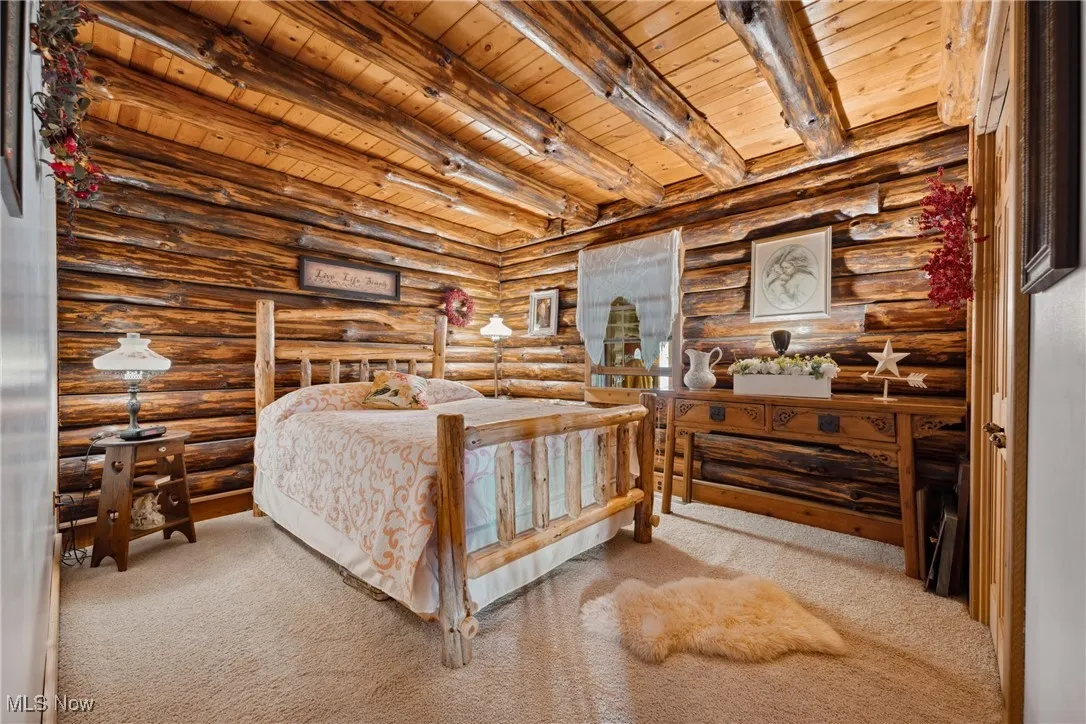 Carpeted bedroom with beam ceiling and wood ceiling