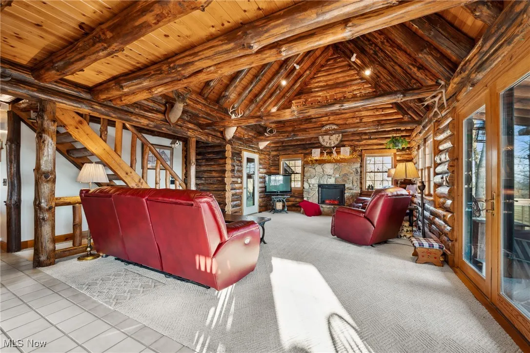 Living room featuring wood ceiling, beam ceiling, stairway, and a fireplace