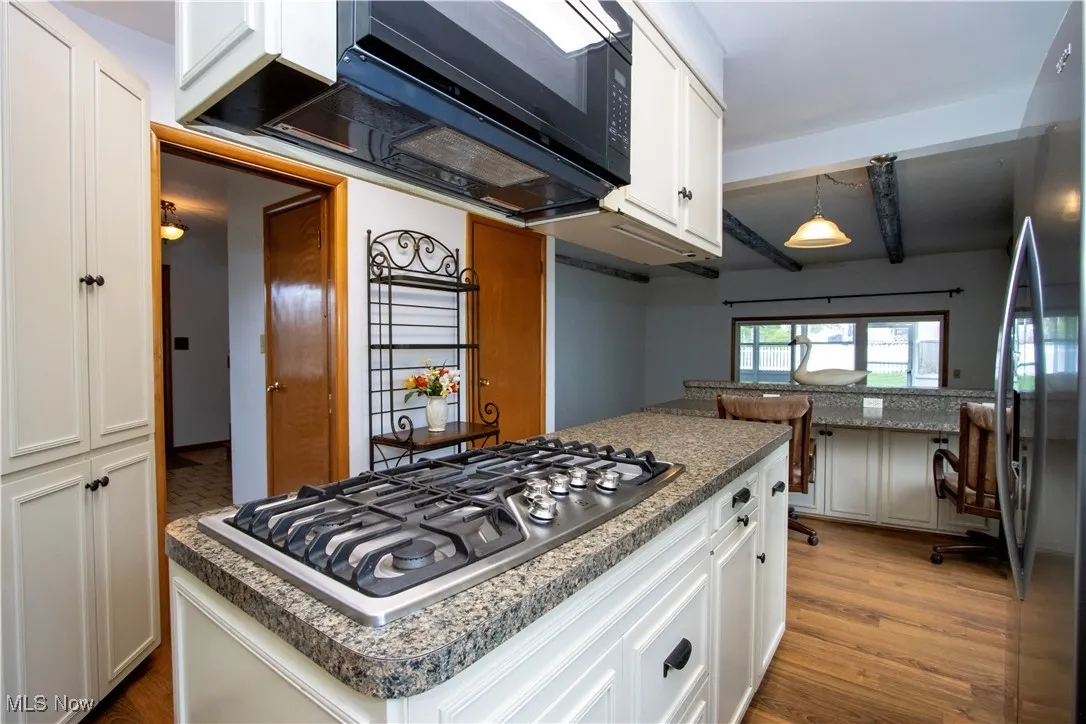Kitchen with white cabinets, stainless steel appliances, and wood finished floors