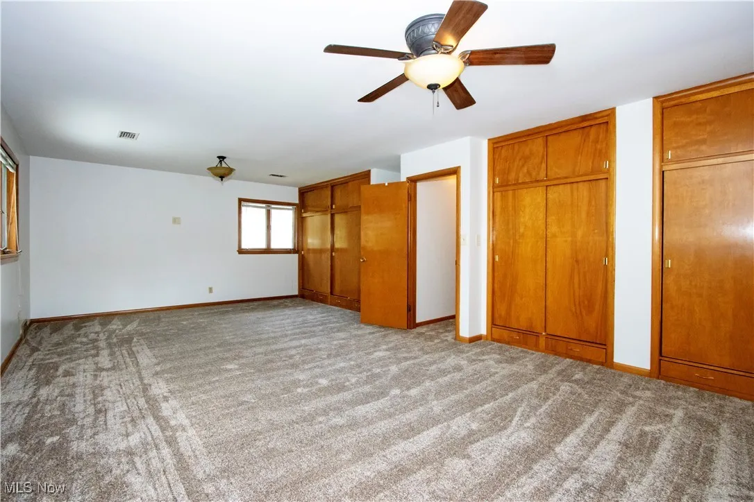 Unfurnished bedroom with baseboards, carpet floors, multiple closets, and visible vents