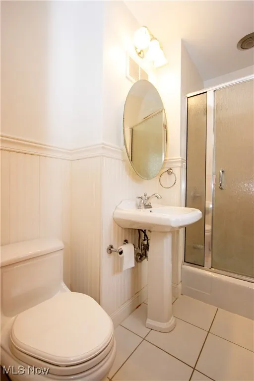 Full bathroom featuring wainscoting, toilet, an enclosed shower, tile patterned flooring, and visible vents
