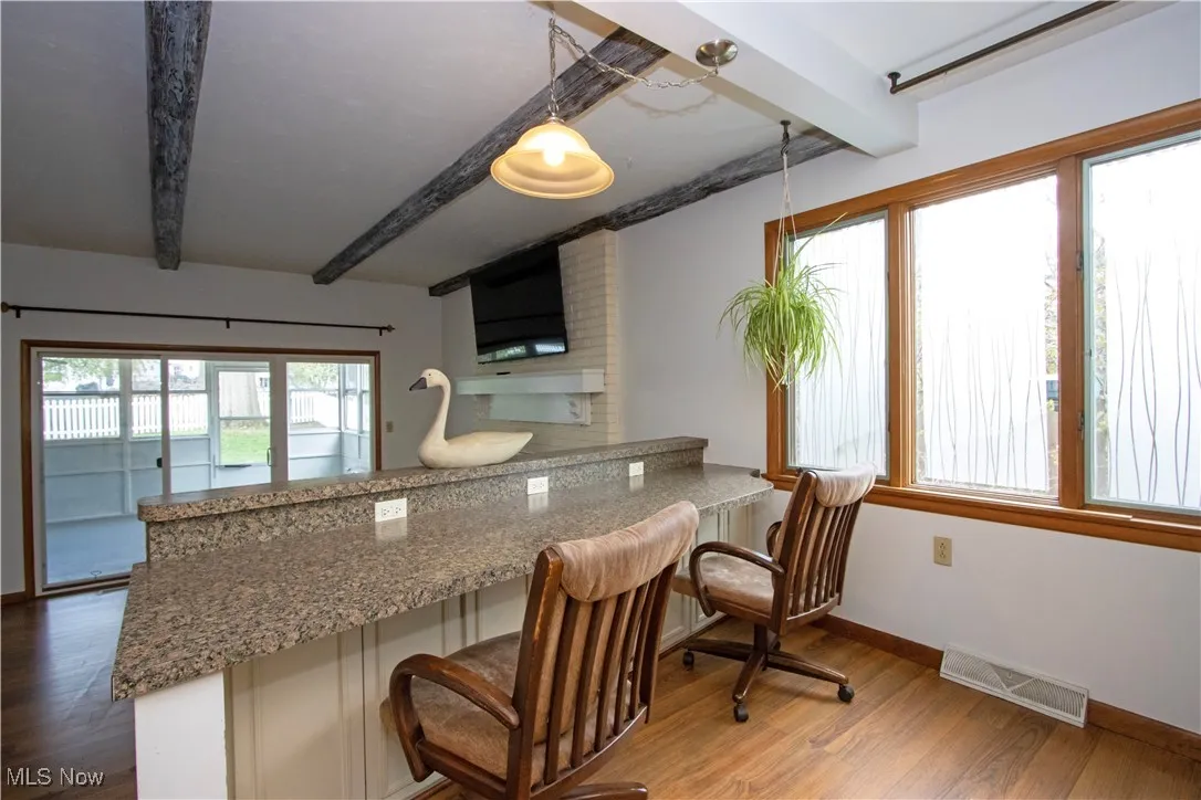 Kitchen featuring a peninsula, wood finished floors, beam ceiling, and visible vents