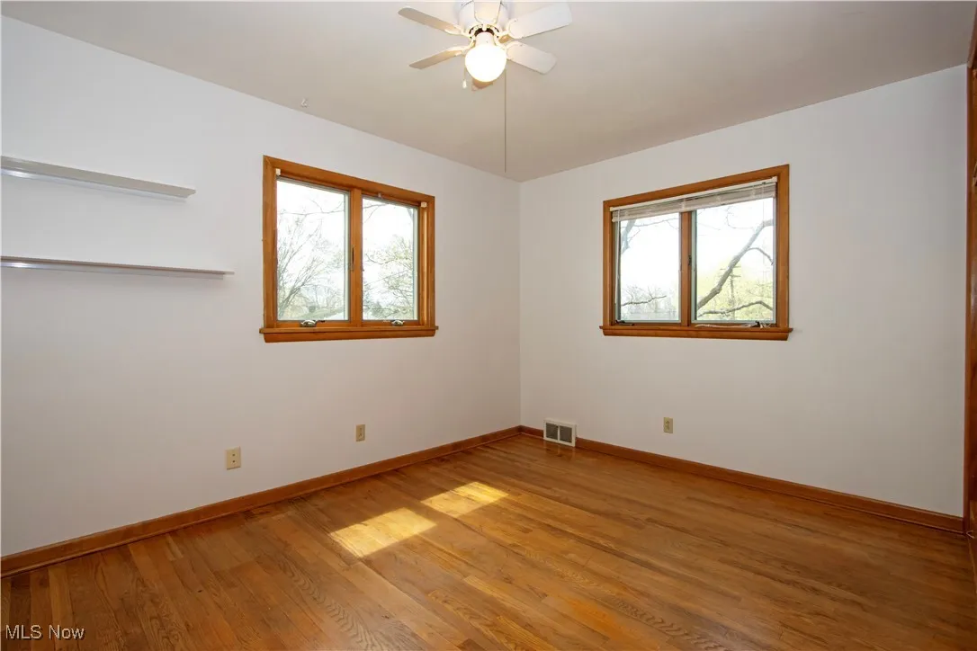 Spare room with light wood-type flooring, baseboards, visible vents, and ceiling fan