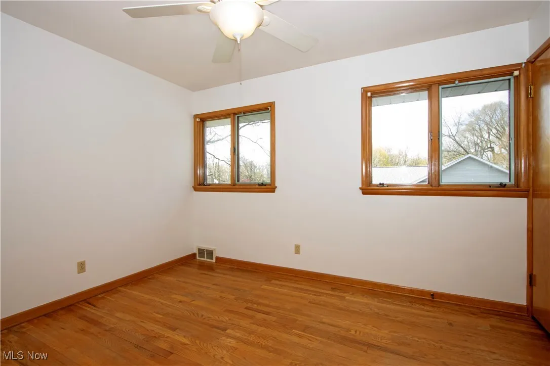 Empty room featuring baseboards, a ceiling fan, visible vents, and light wood-type flooring