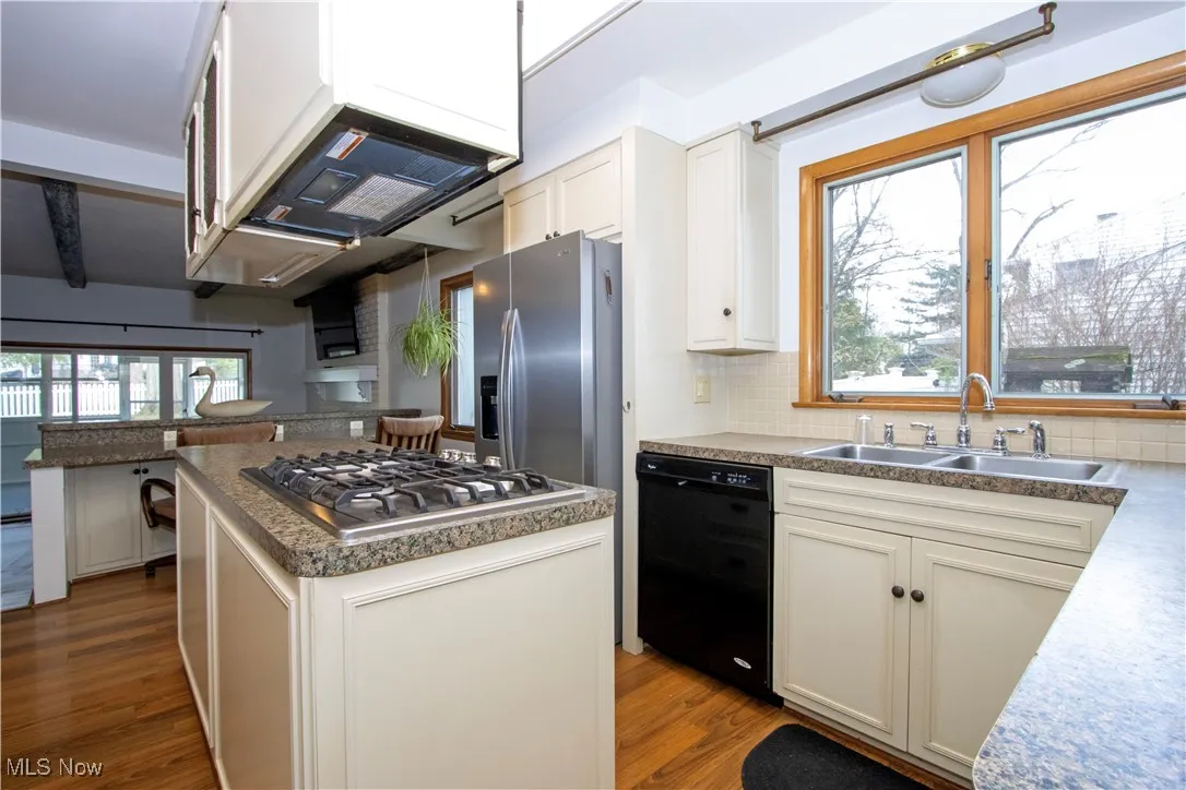 Kitchen with wood finished floors, a center island, stainless steel appliances, and a sink