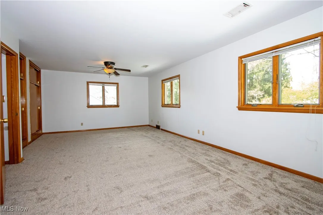 Carpeted spare room featuring visible vents, a ceiling fan, and baseboards