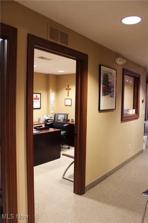 Office area with carpet floors, visible vents, and baseboards