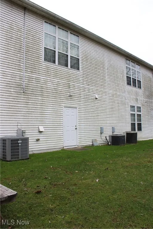 Rear view of property featuring a lawn and central air condition unit