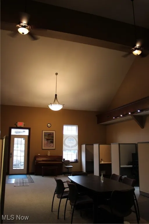 Carpeted dining space featuring a ceiling fan and high vaulted ceiling