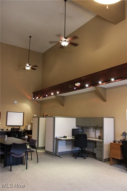 Home office featuring a ceiling fan, high vaulted ceiling, and light carpet
