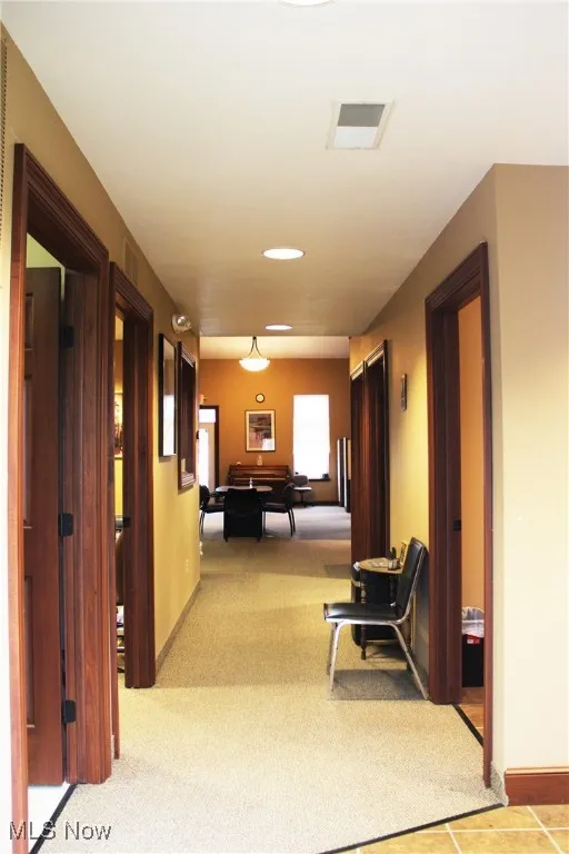 Hallway featuring visible vents, light carpet, baseboards, and recessed lighting