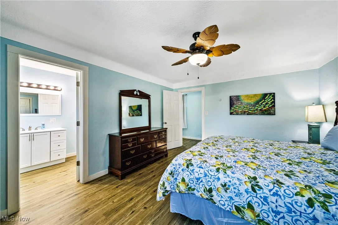Bedroom featuring sink, ceiling fan, light wood-type flooring, and ensuite bathroom