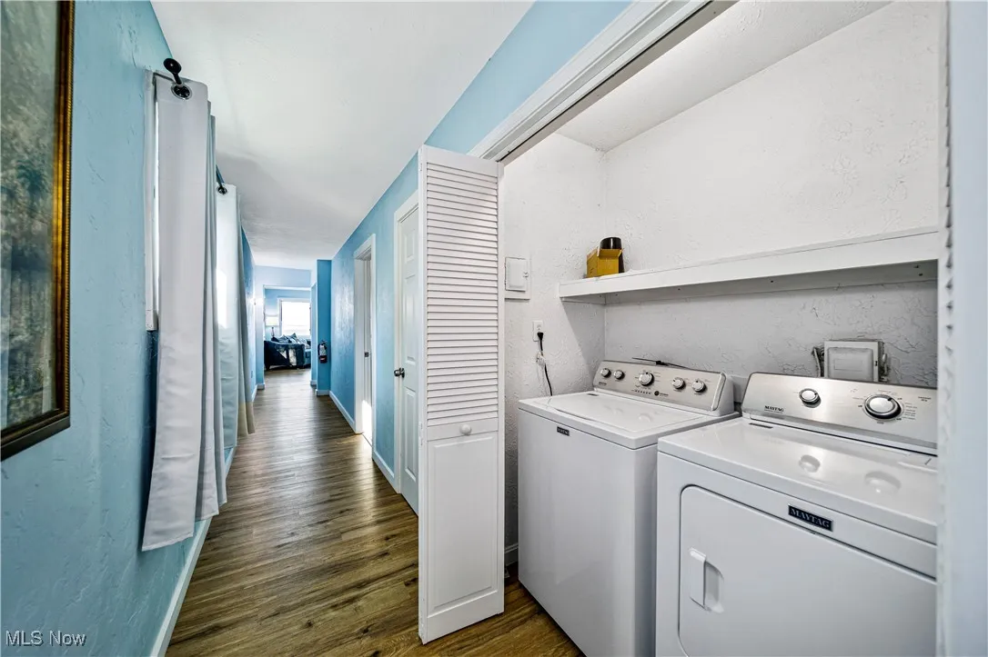 Clothes washing area with washer and dryer and dark hardwood / wood-style flooring
