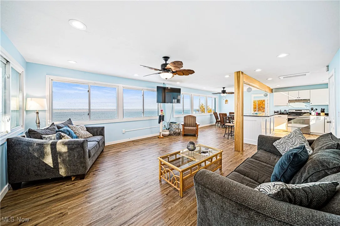 Living room featuring a water view, ceiling fan, and dark wood-type flooring