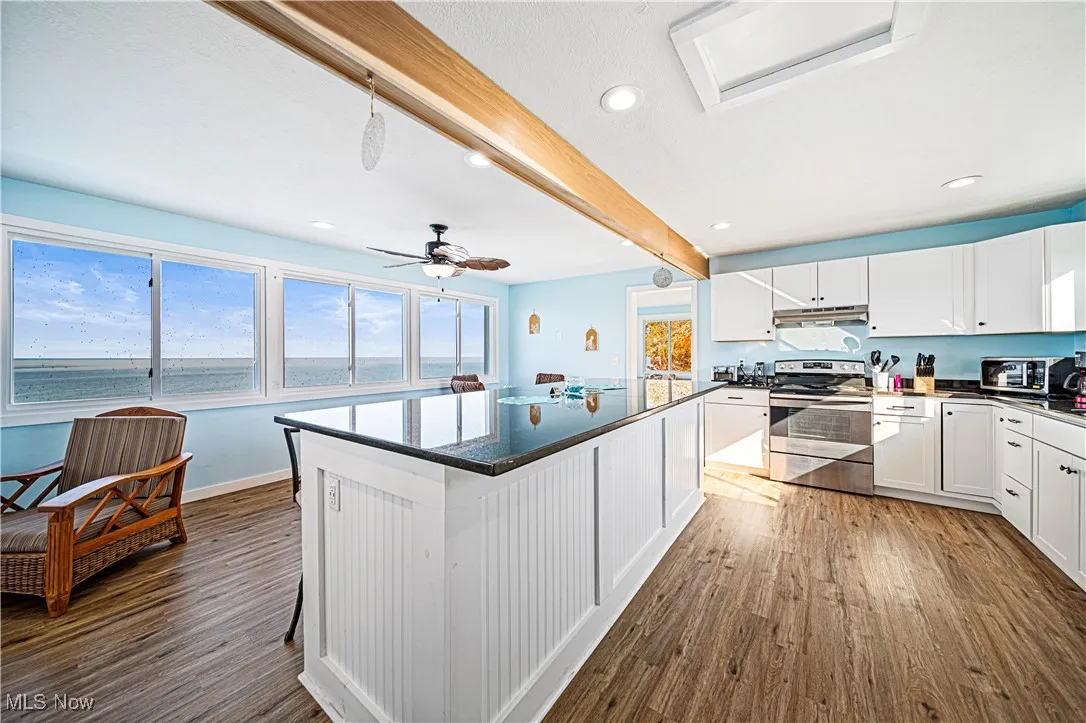 Kitchen featuring a wealth of natural light, a center island, dark hardwood / wood-style flooring, and white cabinets