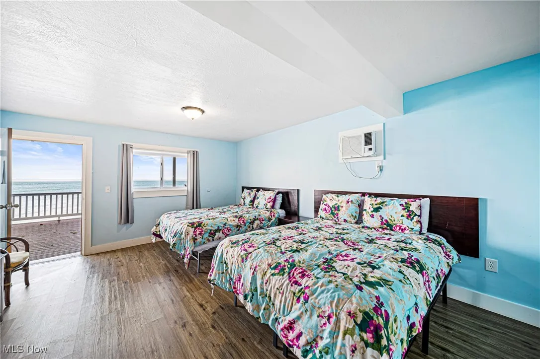 Bedroom with access to outside, dark hardwood / wood-style flooring, and an AC wall unit