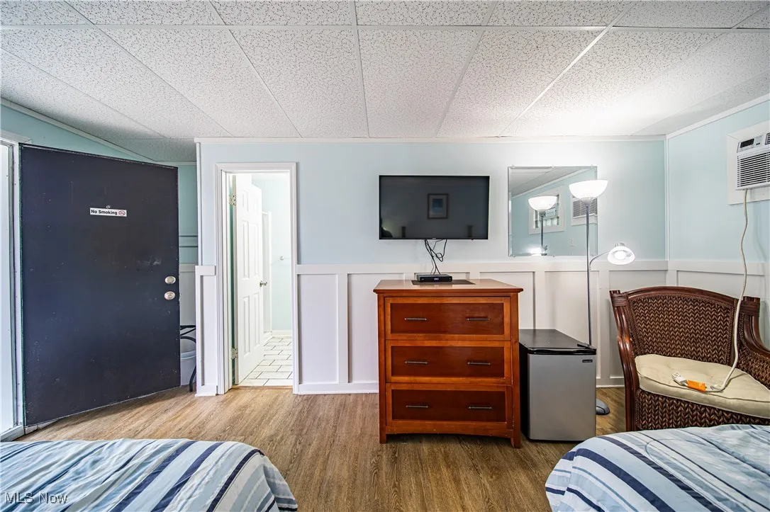Bedroom with a paneled ceiling, light hardwood / wood-style floors, and refrigerator