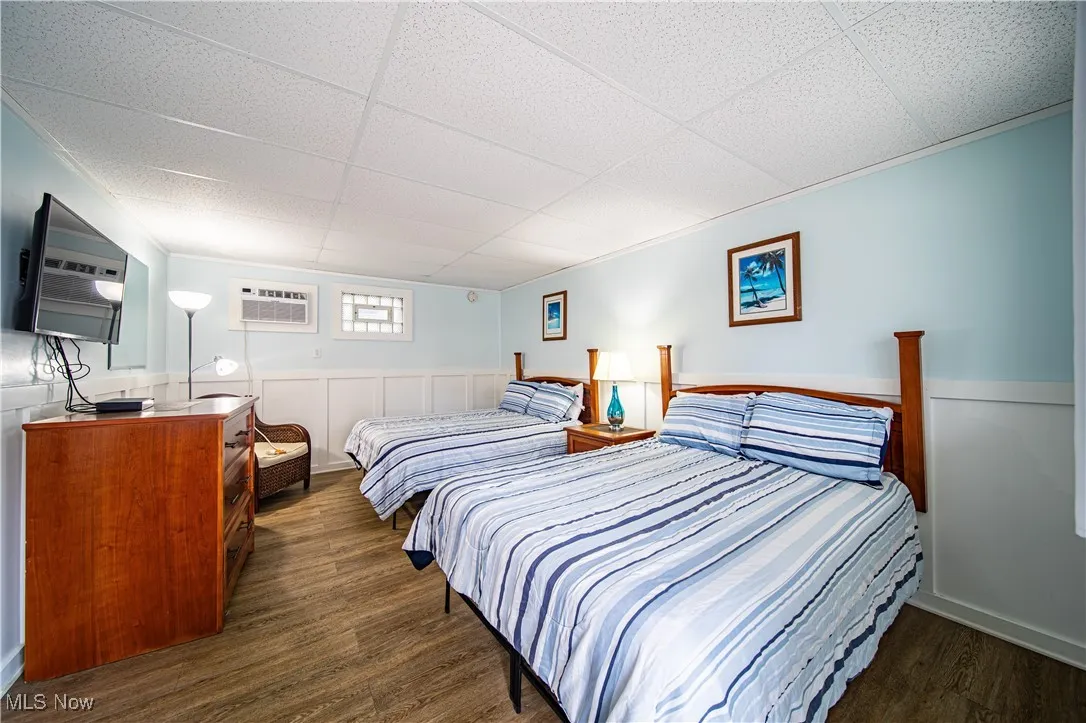 Bedroom with a paneled ceiling, a wall mounted air conditioner, and dark hardwood / wood-style floors