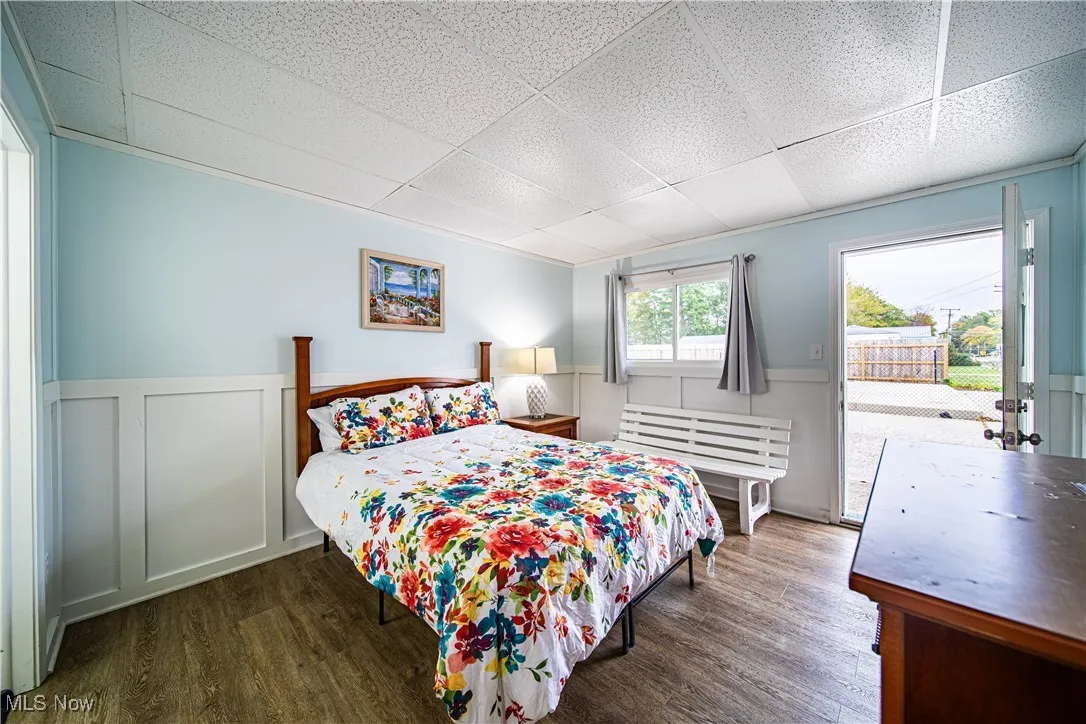 Bedroom featuring access to exterior, dark hardwood / wood-style floors, and a drop ceiling