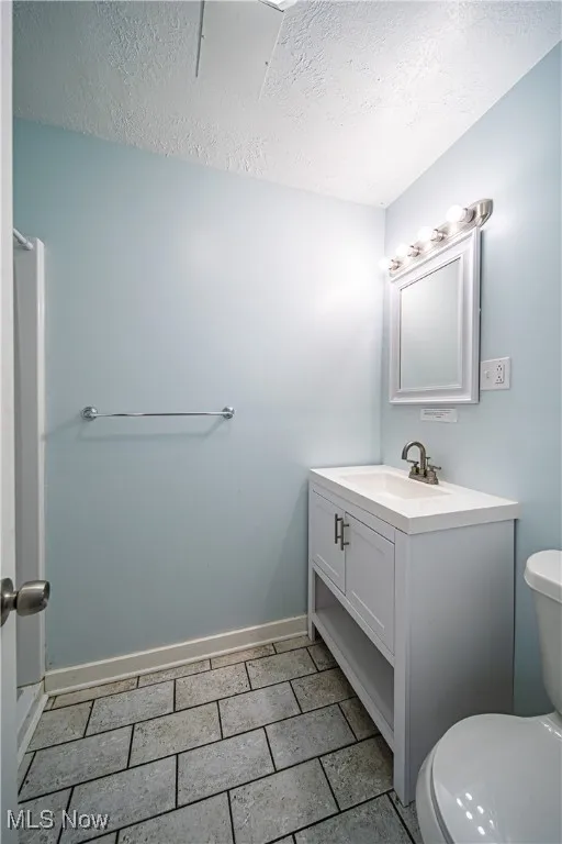Bathroom featuring vanity, a textured ceiling, toilet, and tile flooring
