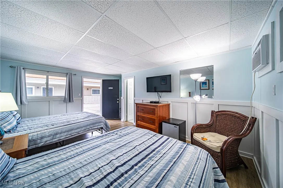 Bedroom featuring hardwood / wood-style floors, a wall mounted air conditioner, and a drop ceiling