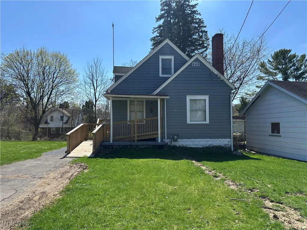 View of front of home featuring a porch, a chimney, and a front yard